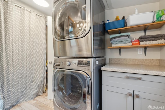 laundry area with stacked washer / dryer and cabinet space