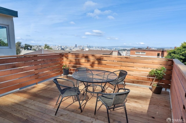 wooden terrace featuring a city view and outdoor dining space