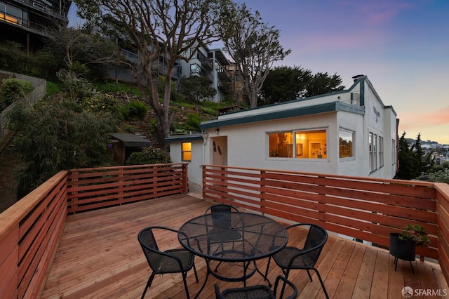 deck at dusk featuring outdoor dining area