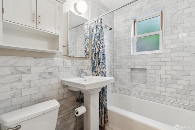 bathroom with a sink, shower / bathtub combination with curtain, toilet, and tile walls