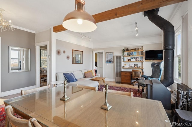 dining space with beamed ceiling, rail lighting, baseboards, and ornamental molding