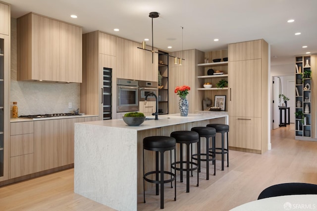 kitchen featuring light hardwood / wood-style flooring, light brown cabinets, and a center island with sink