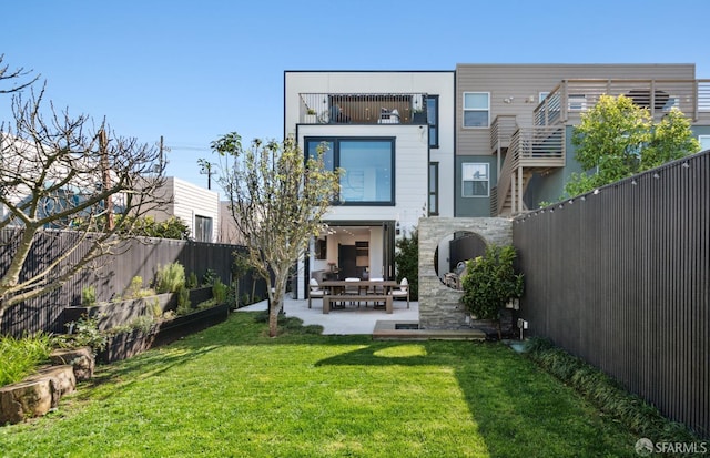 back of house featuring a balcony, a lawn, and a patio area