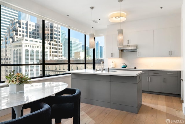 kitchen featuring gray cabinets, sink, light hardwood / wood-style floors, and decorative light fixtures