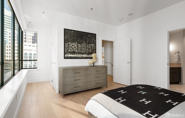 bedroom featuring ensuite bathroom, light hardwood / wood-style flooring, and multiple windows