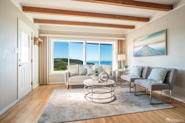 living area featuring light wood-style floors, baseboards, and beamed ceiling