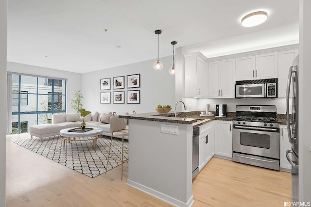 kitchen featuring light hardwood / wood-style floors, white cabinetry, kitchen peninsula, and appliances with stainless steel finishes