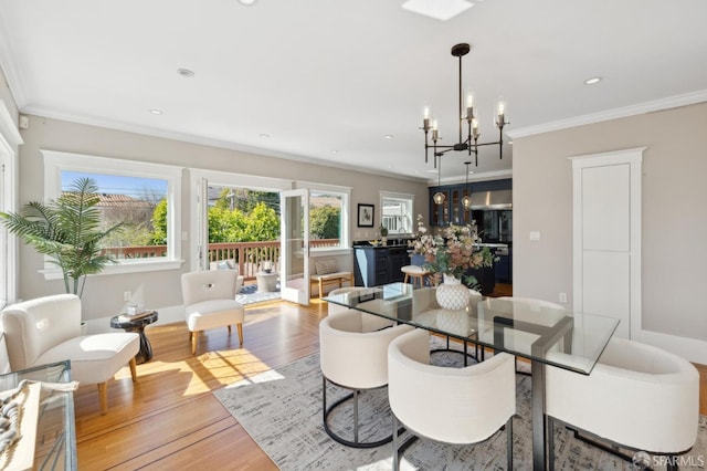 dining space with ornamental molding, recessed lighting, light wood-style flooring, and an inviting chandelier