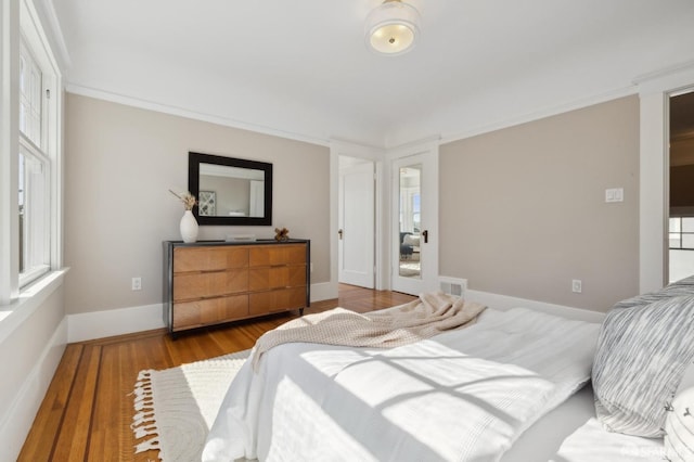 bedroom featuring visible vents, crown molding, baseboards, and wood finished floors