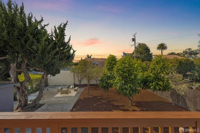 yard at dusk featuring a patio area and fence