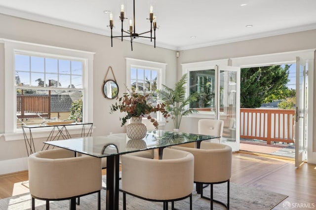 dining room featuring ornamental molding, a notable chandelier, plenty of natural light, and wood finished floors