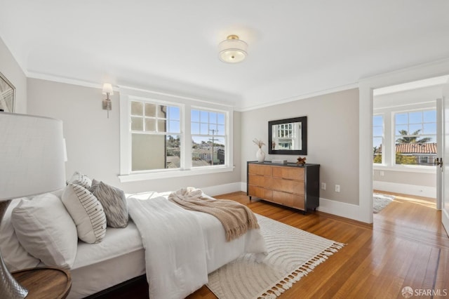 bedroom featuring crown molding, baseboards, and wood finished floors