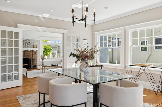 dining area with a notable chandelier, recessed lighting, ornamental molding, a brick fireplace, and wood finished floors