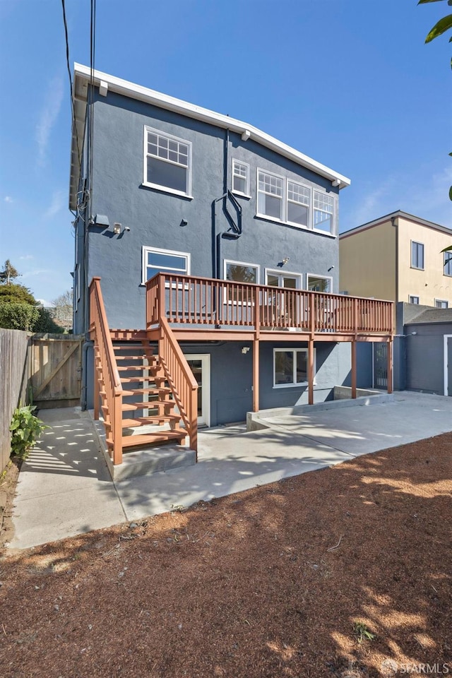 rear view of property featuring stucco siding, stairway, a patio area, fence, and a deck