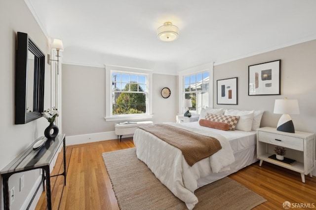 bedroom featuring crown molding, baseboards, and wood finished floors