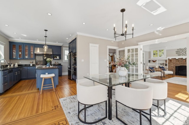 dining room featuring recessed lighting, a fireplace, baseboards, ornamental molding, and light wood-type flooring