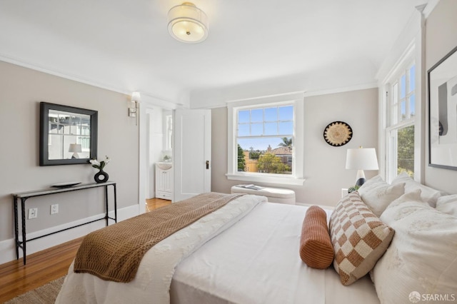 bedroom with crown molding, baseboards, and wood finished floors