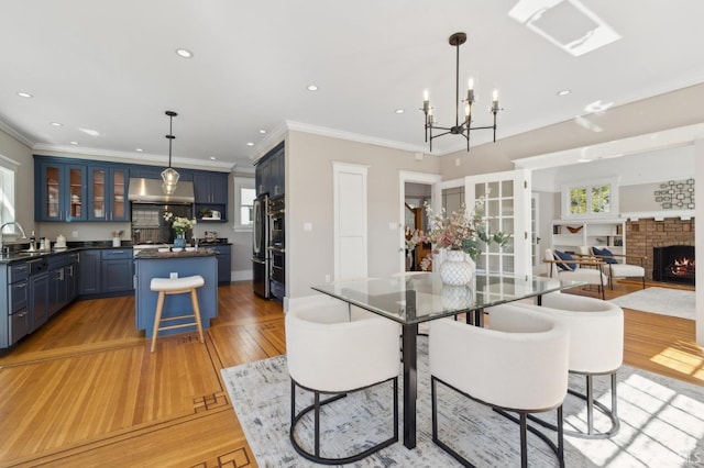 dining area with recessed lighting, light wood-style flooring, ornamental molding, a brick fireplace, and baseboards