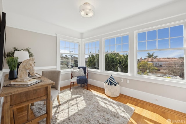 living area with baseboards, wood finished floors, and a healthy amount of sunlight