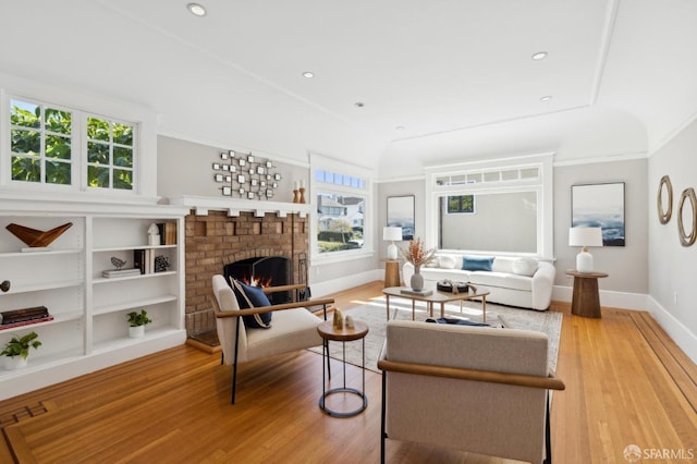 living room with a brick fireplace, baseboards, and wood finished floors