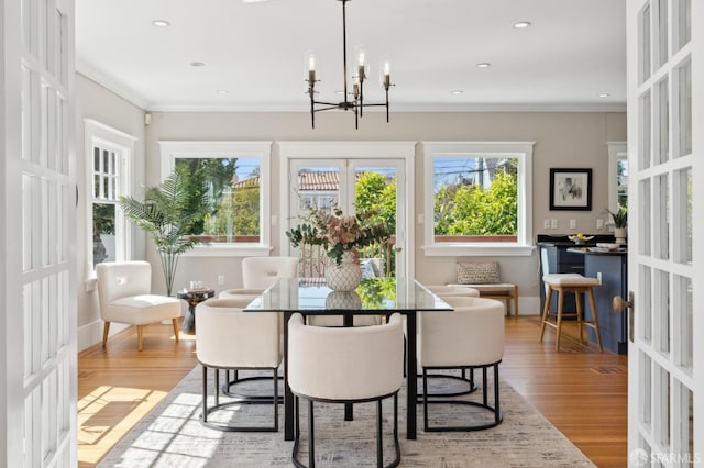 dining room featuring ornamental molding, french doors, wood finished floors, and a notable chandelier