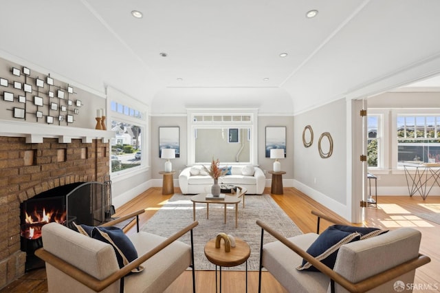 living area with recessed lighting, a brick fireplace, baseboards, and wood finished floors