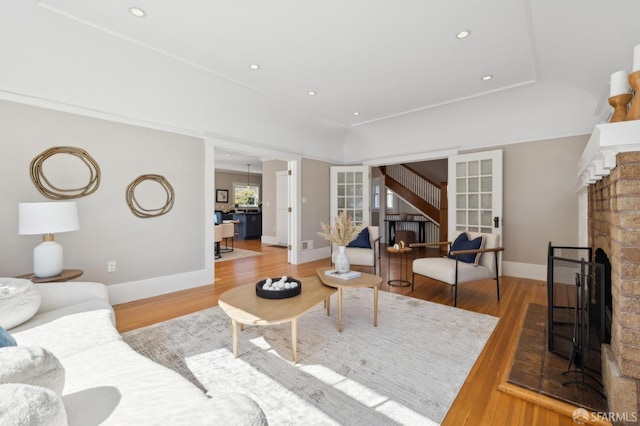 living area with a fireplace with raised hearth, wood finished floors, and baseboards