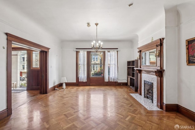 unfurnished living room featuring a fireplace, baseboards, and an inviting chandelier