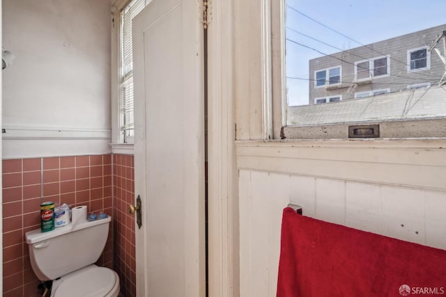 bathroom with toilet and tile walls