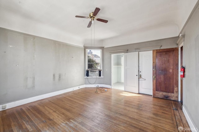 empty room featuring a ceiling fan, cooling unit, baseboards, and hardwood / wood-style floors