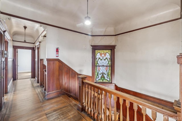 hallway featuring an upstairs landing, dark wood finished floors, crown molding, and wainscoting