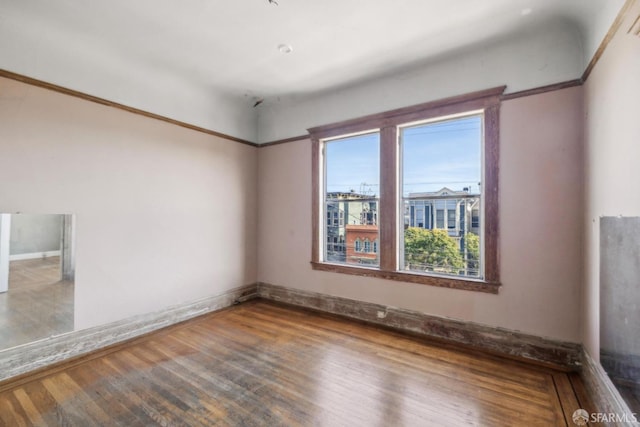 spare room featuring baseboards and wood finished floors