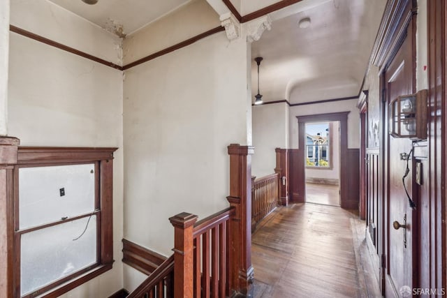 hallway with ornamental molding, wood finished floors, and an upstairs landing