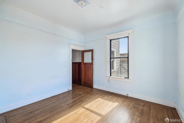 spare room with baseboards and wood finished floors