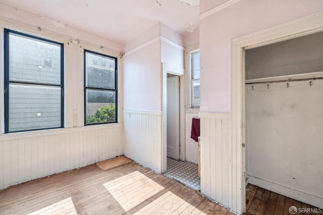 unfurnished bedroom featuring a closet, a wainscoted wall, and hardwood / wood-style floors