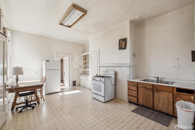 kitchen featuring light countertops, visible vents, brown cabinetry, a sink, and white appliances