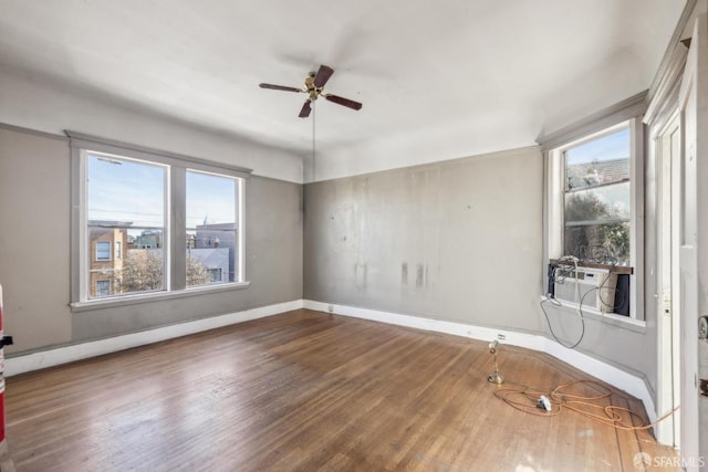 unfurnished room featuring a ceiling fan, cooling unit, baseboards, and wood finished floors