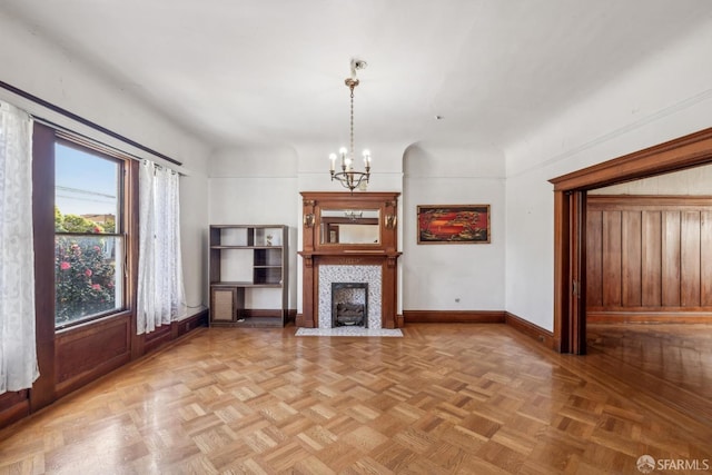 unfurnished living room featuring baseboards, a fireplace, and a chandelier