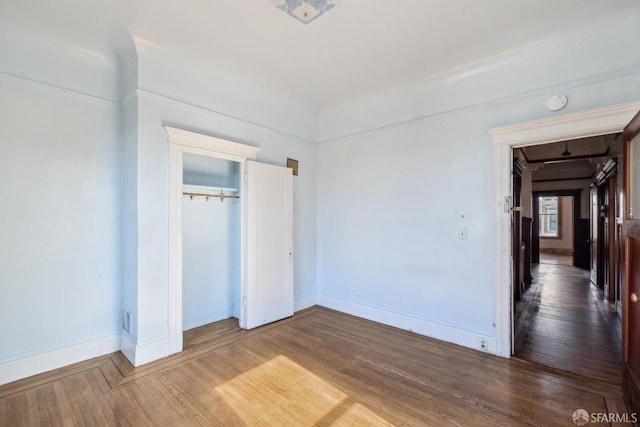 unfurnished bedroom featuring a closet, baseboards, and wood finished floors