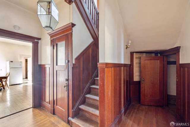 stairway featuring wood finished floors and wainscoting