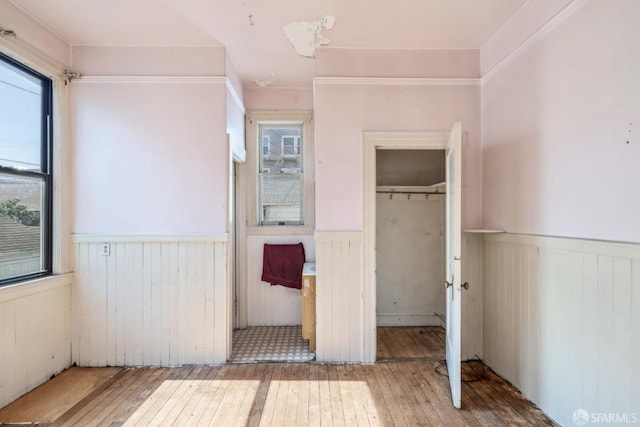 unfurnished bedroom featuring a closet, wainscoting, and hardwood / wood-style flooring