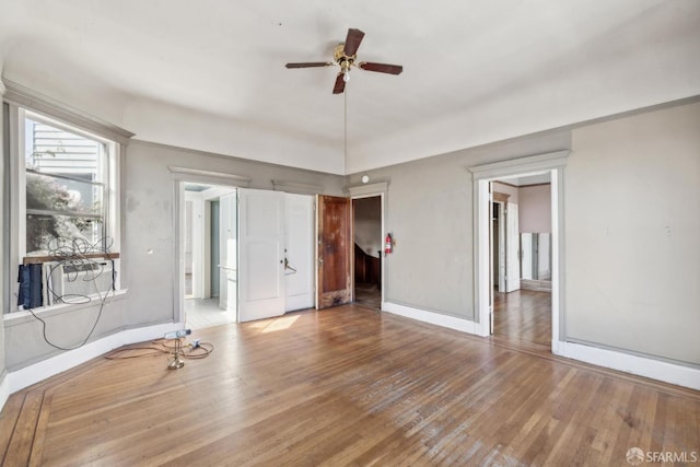 empty room with a ceiling fan, baseboards, and wood finished floors