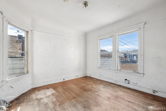 spare room featuring wood finished floors and a healthy amount of sunlight