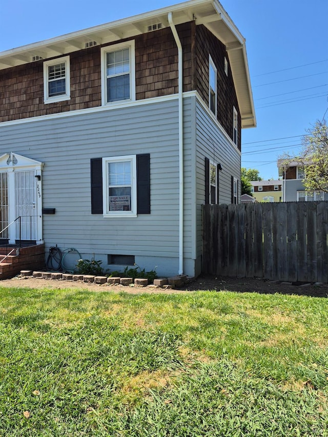 view of side of home featuring a lawn, entry steps, and fence
