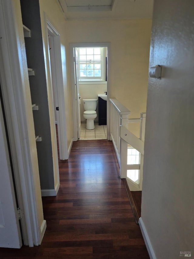 corridor featuring baseboards, dark wood finished floors, and an upstairs landing