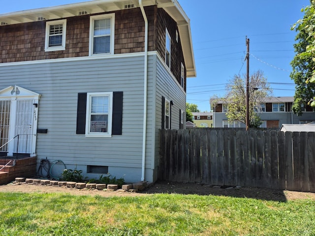view of side of home with fence and a lawn