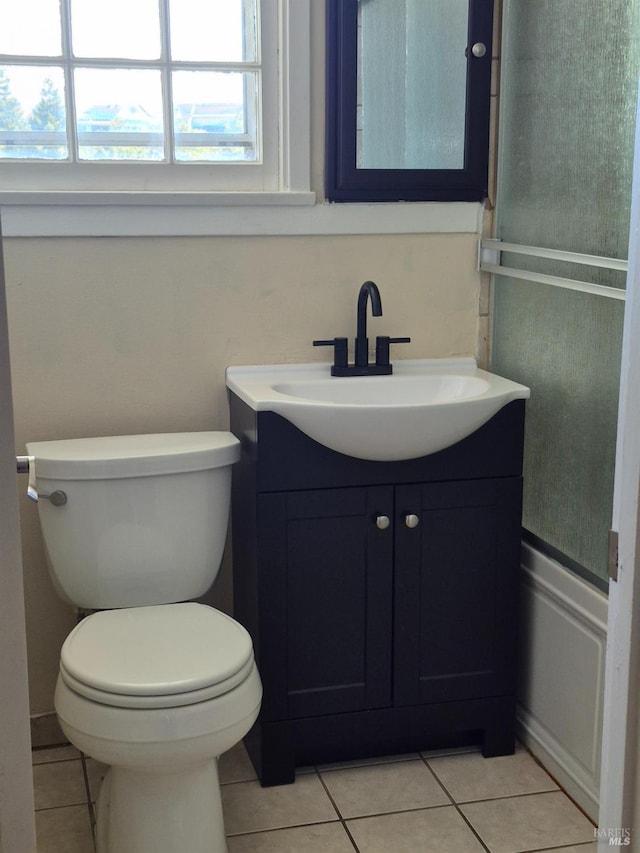 half bathroom with toilet, tile patterned flooring, and vanity