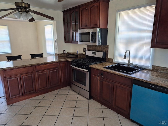 kitchen featuring a sink, a peninsula, stainless steel appliances, a healthy amount of sunlight, and ceiling fan