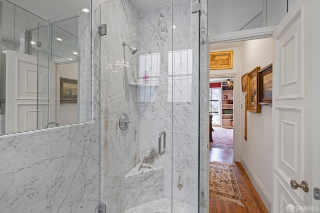 full bath featuring a marble finish shower and wood finished floors