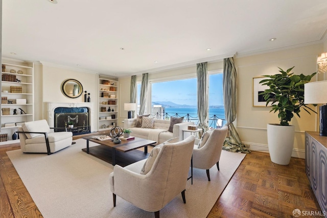 living room with built in features, a fireplace, ornamental molding, and a water view